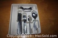 Full view of cutlery set organized in white plastic holder tray showing knives, forks, teaspoons, tablespoons.