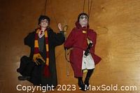 Two Harry Potter marionette puppets standing on wooden surface, one with Gryffindor scarf, one in Quidditch robes holding broomstick