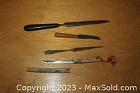 Top down view of all four letter openers on wooden surface showing sizes and details