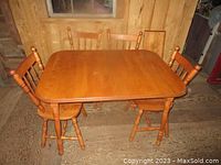 Maple dining table with four matching chairs shown from an angle, illustrating the finish and style.