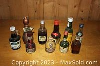 Photo showing seven vintage miniature liquor bottles in various shapes and sizes on a wooden surface