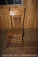 Full view of the wooden rocking chair showing the seat, legs, and backrest with spindle design.