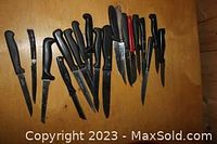 Top view of assortment of small kitchen knives with black handles on a wooden table.