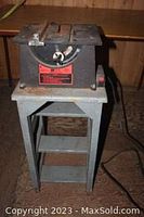 Small table saw with 4-inch blade on a metal stand, front view