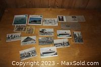 Assortment of vintage postcards laid out on a wooden surface, showing ships, buildings, and other scenes.