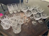 Photo of 25 crystal glasses including 10 highball, 7 lowball, and 8 champagne glasses with patterns.