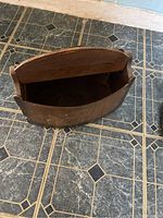 Top-down view of vintage wooden sewing storage box showing open interior and curved lid.