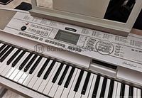 Close-up image of the Yamaha DGX500 keyboard keys and control panel, showing the brand logo, multiple functional buttons, and LCD screen.