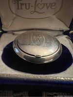 Closed antique sterling silver compact with engraved top monogram W in velvet-lined Tru-Love box.