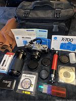 Photo showing all items including Canon AE-1 camera, lenses, tripod, remote switch, filter, software CD, manuals, and carrying case.