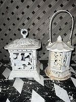Both cast iron antique lanterns side-by-side, showing their overall shape, design, and condition.
