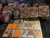 Photo shows multiple Yu-Gi-Oh 5D's themed metal tins with colorful fantasy dragon artwork, along with a card album with various collectible cards inserted and scattered Yu-Gi-Oh cards.