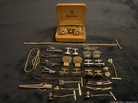 Full lot displayed on dark fabric showing cuff links pairs, tie clips, and tie chains with boxed Spartan cuff links.