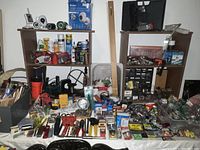 Wide view of assorted tools and hardware laid out on tables and shelves, including boxes, spray cans, and hand tools.