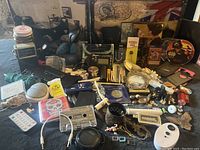 Wide view of the lot showing several grouped vintage items, electronics, and memorabilia including guitar tuners, old radios, framed photos, and collectible pieces.