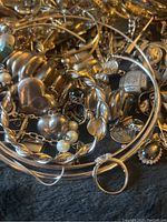 Photo showing assorted metal jewelry including rings, bracelets, and chains with some pearl and bead accents.