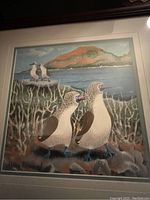 Full framed painting showing four blue-footed boobies standing on rocks and coral near the shore with a mountain and ocean in the background.