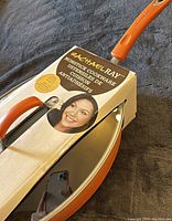 Photo of the boxed Rachael Ray non-stick oval sauté pan showing branding and packaging with pan handle visible.