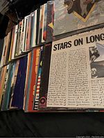 Angled view showing a stack of various vinyl records with visible spines and cover edges revealing multiple albums.