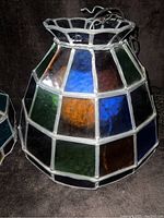 Close-up of the large stained glass swag light showing multi-colored glass panels including blue, green, orange, with a missing small side piece visible