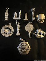 Top down view of 10 sterling silver charms showing detailed representations of landmarks and symbols on black background.