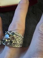 Sterling silver multi-gem ring worn on finger, showing intricate band and multi-stone setting.