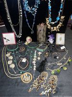 Full display of jewelry lot including turquoise necklaces, various pins, bracelets, and earrings arranged on black fabric.