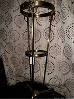 Full view of the vintage solid brass pot stand showing overall height and structure with circular rings and three legs.