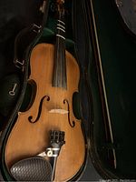 Violin in open case showing top plate, chinrest, fingerboard, tailpiece and bow stored alongside