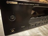 Close-up of the front left side showing Yamaha logo, model number HTR-6025, standby/on button, headphone jack, and speaker switch.