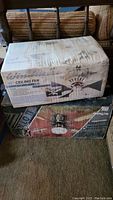Two unopened boxes stacked showing packaging for 42-inch Windmere ceiling fan on top and Apollo II fan on bottom with some water stains on boxes.