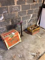 Overview of the lot showing the EZ Weaver box, metal shoe repair stand, and vintage Pepsi wooden crate on a concrete floor against a cinder block wall.