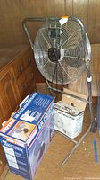 8-inch high velocity fan on metal frame next to boxed fans