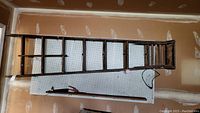 Full length overhead view of the wooden step ladder lying on floor showing all steps and rails.