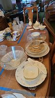 View of dining table with assortment of Mikasa floral dinnerware, Lenox gold trimmed candy dish, and several gold tone trimmed glass pieces and bowls