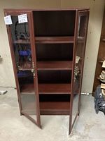 Front view of open bookcase showing four shelves inside and glass doors.
