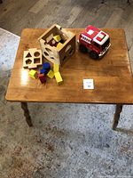 Wooden child's table with the wooden shape sorting toy and red-white fire truck placed on top