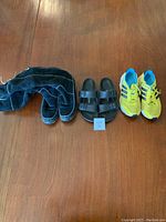 Photo of three items: Timberland boots, Birkenstock sandals, Adidas runners lined up on a wooden floor.