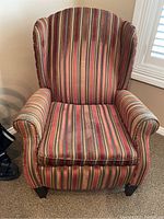 Front view of the upholstered wingback chair showing striped fabric and padded armrests