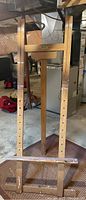 Full view of wooden artist easel showing height and adjustable parts with peg holes and bottom shelf