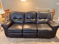 Front view of dark brown leather La-Z-Boy reclining couch with three seats, showing discoloured corner cushion on the left seat