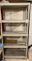 Full view of the five-level beige plastic shelf unit against a basement wall.