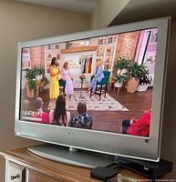 Sony 40 inch flat screen TV powered on showing a TV show image, placed on wooden TV stand.