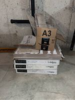 Three stacked closed Enigma porcelain tile boxes with labels showing 7 pieces each, size 18x18 inches, and one smaller box on top with some scraps.