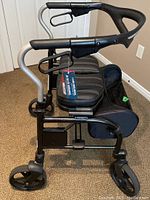 Side view of Trillium walker showing padded seat, black storage bag, adjustable height frame, and hand brakes.