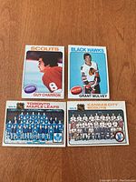 Four 1975/76 O-Pee-Chee hockey cards showing two individual player cards (Guy Charron and Grant Mulvey) and two team cards (Toronto Maple Leafs and Kansas City Scouts). Cards laid out on a wooden surface.