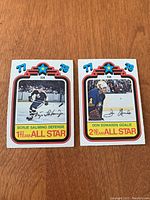 Front photo of Borje Salming and Don Edwards 1978/79 OPC All Star hockey cards placed side by side on a wooden surface.