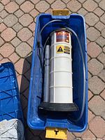 Top view of the Fluid Evacuator Plus inside blue plastic carrying container showing flexible hose attached