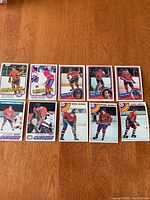 Ten vintage Montreal Canadiens hockey trading cards laid out on wooden floor showing front face of cards with player photos and names.