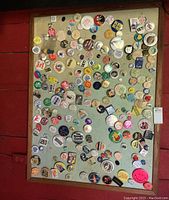 Full view of the wood framed pin board with numerous vintage button pins attached.
